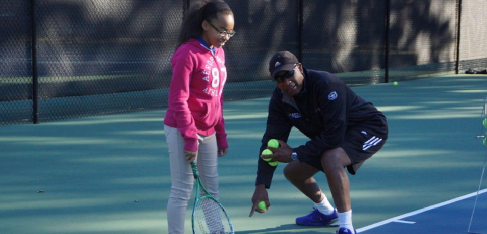 Andre coaching a young player on the tennis court
